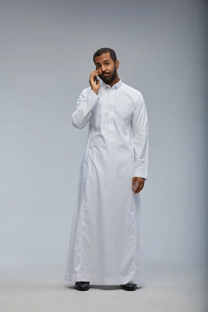 Saudi Man in White Thobe Talking on Smartphone
