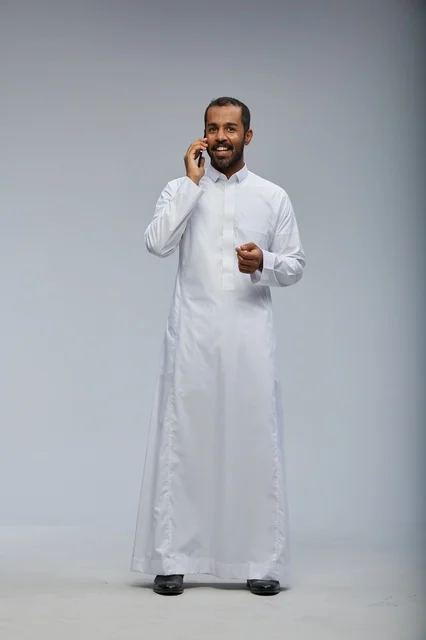 Saudi Man in White Thobe Talking on Smartphone