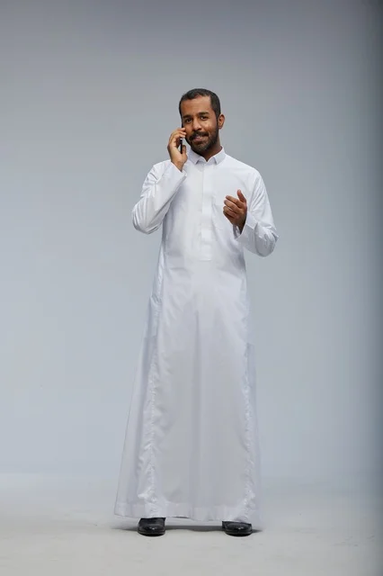 رجل سعودي بالثوب الأبيض يتحدث بالهاتف الذكي في الاستوديو