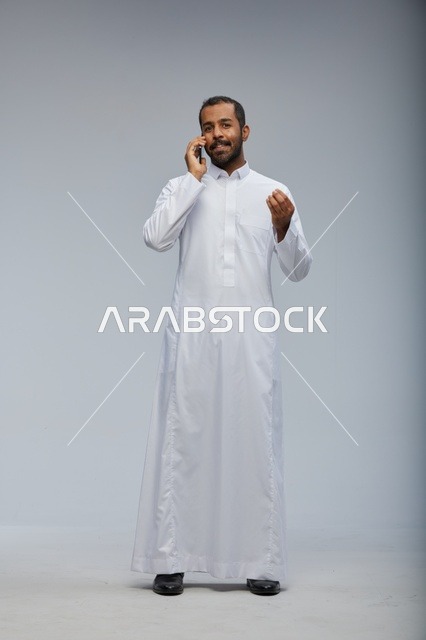 Saudi Man in White Thobe Talking on Smartphone Studio