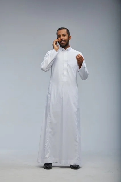 رجل سعودي بالثوب الأبيض يتحدث بالهاتف الذكي في استوديو