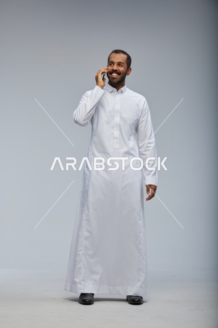 Saudi Man in White Thobe Talking on Smartphone Studio