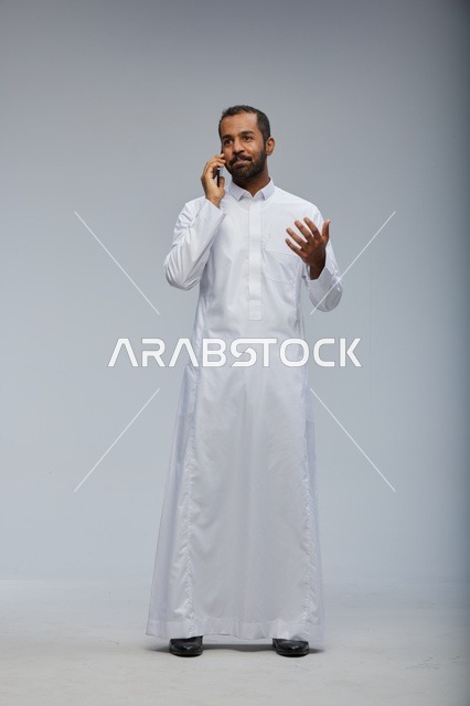 Saudi Man in White Thobe Talking on Smartphone