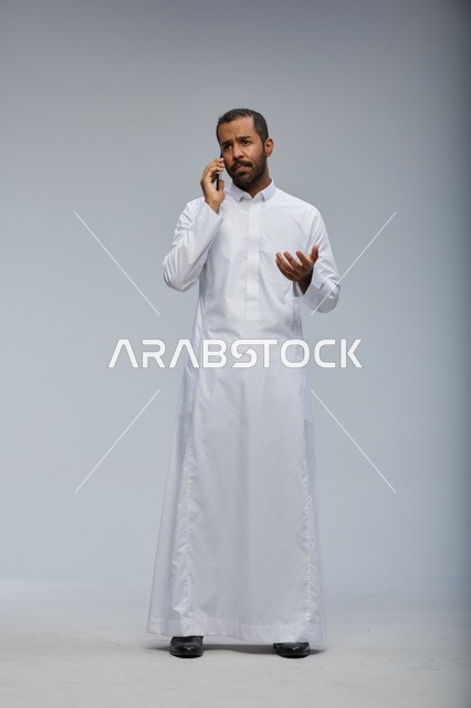 Saudi Man in White Thobe Talking on Smartphone Studio