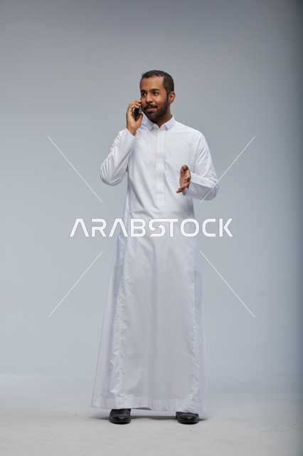 Saudi Man in White Thobe Talking on Smartphone Studio