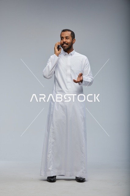 Saudi Man in White Thobe Talking on Smartphone Studio
