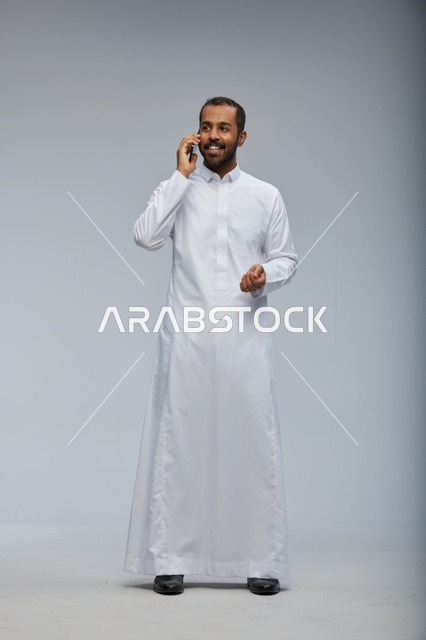 Saudi Man in White Thobe Talking on Smartphone Studio