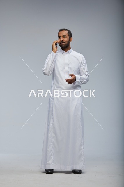 Saudi Man in White Thobe Talking on Smartphone