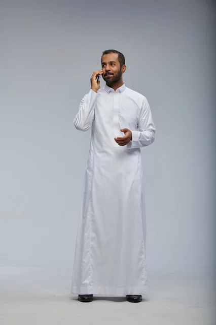 Saudi Man in White Thobe Talking on Smartphone