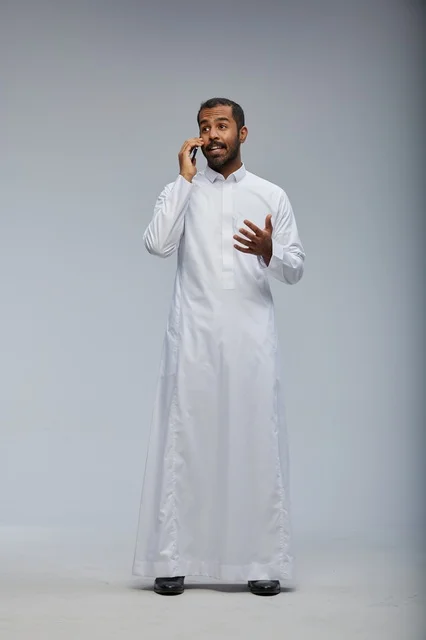 رجل سعودي بالثوب الأبيض يتحدث بالهاتف الذكي في الاستوديو