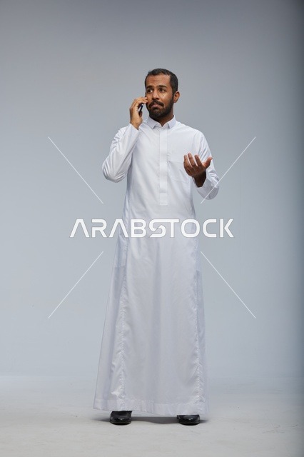 Saudi Man in Traditional Thobe Talking on Smartphone