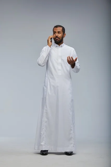 رجل سعودي يرتدي الثوب التقليدي يتحدث عبر الهاتف الذكي
