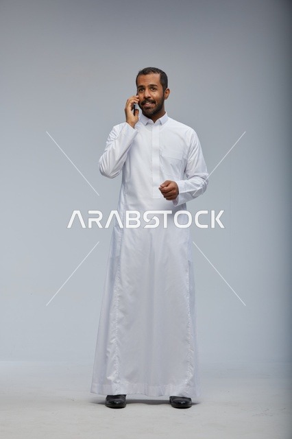 Saudi Man in White Thobe Talking on Smartphone Studio