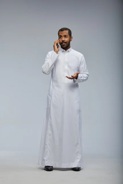 Saudi Man in Traditional White Thobe Talking on Smartphone