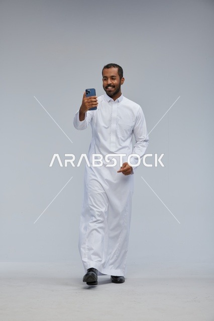 Saudi Man in White Thobe Taking Selfie on Grey Background