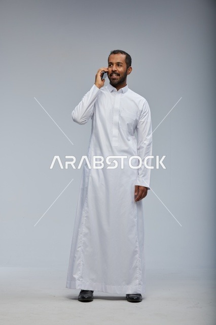 Saudi Man in White Thobe Talking on Smartphone Studio