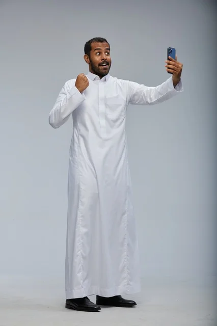 رجل سعودي بالثوب الأبيض يلتقط سيلفي بالهاتف الذكي