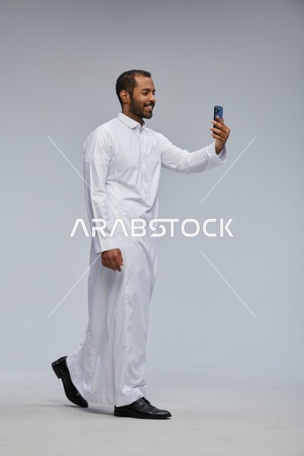رجل سعودي بالثوب الأبيض يلتقط صورة سيلفي بالجوال