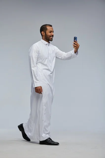 رجل سعودي بالثوب الأبيض يلتقط صورة سيلفي بالجوال