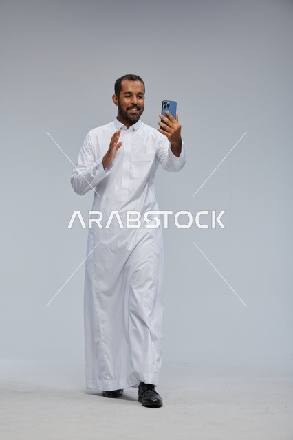 رجل سعودي بالثوب الأبيض مع هاتف ذكي في الاستوديو
