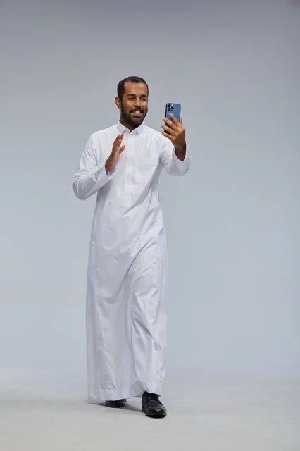 رجل سعودي بالثوب الأبيض مع هاتف ذكي في الاستوديو