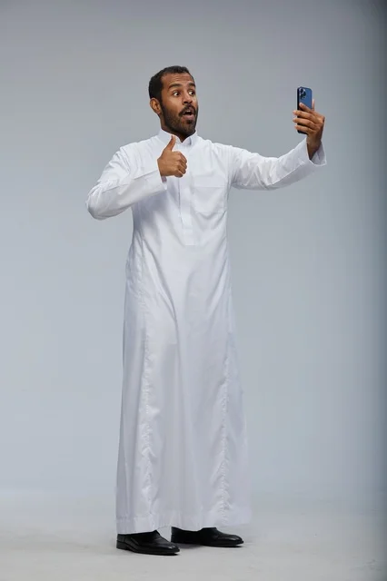 Saudi Man in White Thobe Taking Selfie with Smartphone
