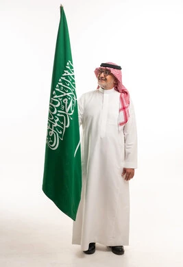رجل سعودي يحمل علم المملكة في الاستوديو