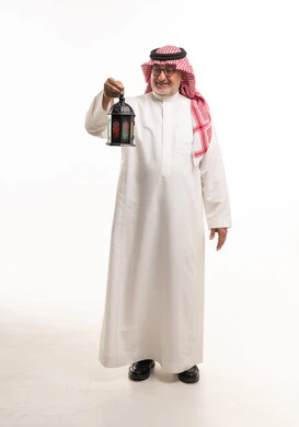 رجل سعودي مسن يحمل فانوس رمضان بخلفية بيضاء