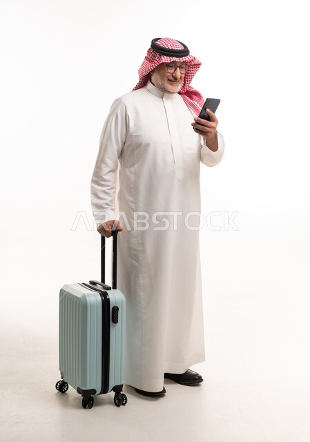 رجل سعودي مسن مع حقيبة سفر وهاتف ذكي