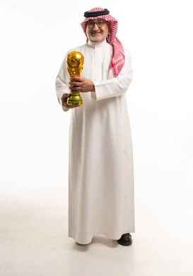 رجل سعودي يمسك بكأس العالم لكرة القدم بخلفية بيضاء