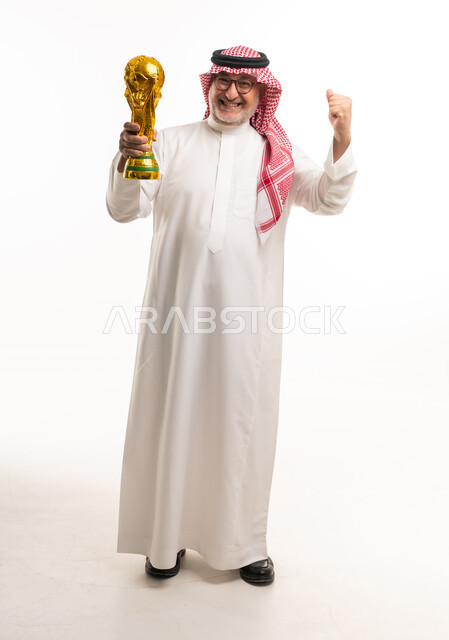 رجل سعودي مسن يحمل كأس العالم بالزي التقليدي