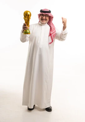 رجل سعودي مسن يحمل كأس العالم بالزي التقليدي