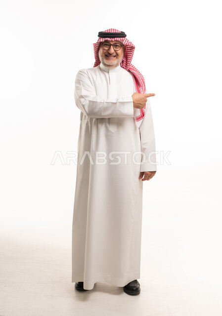 رجل سعودي يرتدي الثوب التقليدي يشير للجانب بخلفية بيضاء