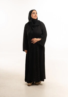 امرأة إماراتية بالعباءة السوداء على خلفية بيضاء