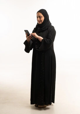 امرأة إماراتية بالعباءة السوداء تستخدم الجوال