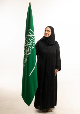 امرأة سعودية بالعباءة مع العلم الوطني للمملكة