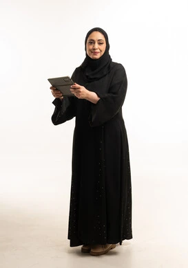 امرأة عربية بالعباءة تمسك جهاز لوحي في الاستوديو