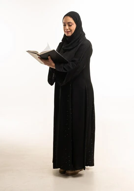 امرأة إماراتية تقرأ كتاباً على خلفية بيضاء