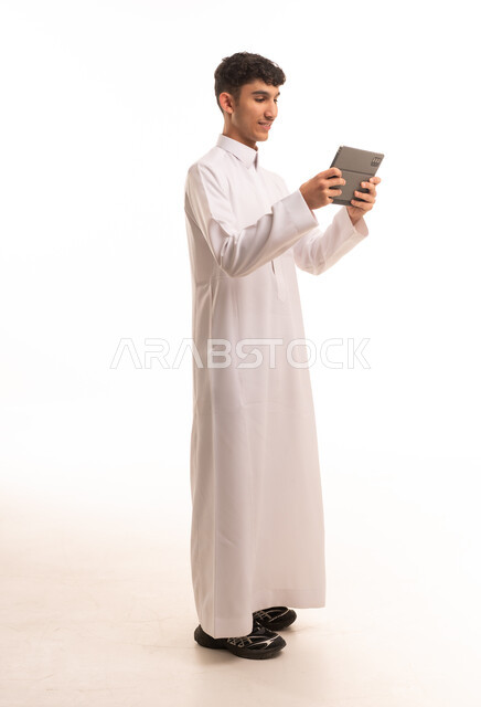 شاب سعودي بالثوب التقليدي يستخدم جهاز لوحي