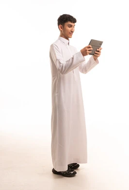 شاب سعودي بالثوب التقليدي يستخدم جهاز لوحي