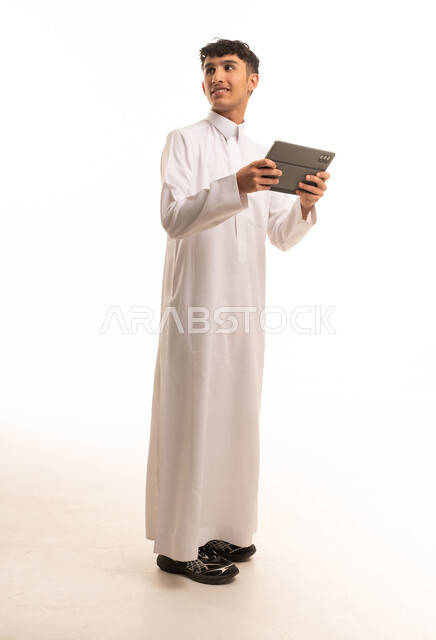 رجل سعودي بالثوب الأبيض يمسك بجهاز لوحي رقمي