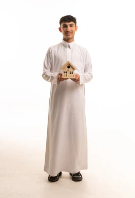 رجل سعودي بالثوب يحمل مجسم منزل خشبي