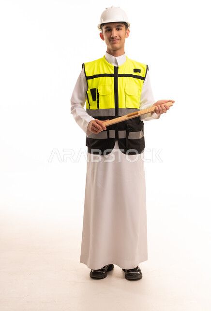 مهندس سعودي بالثوب وسترة السلامة يحمل مخططا هندسيا