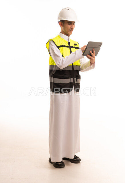 مهندس سعودي بالثوب وخوذة السلامة يستخدم جهاز لوحي