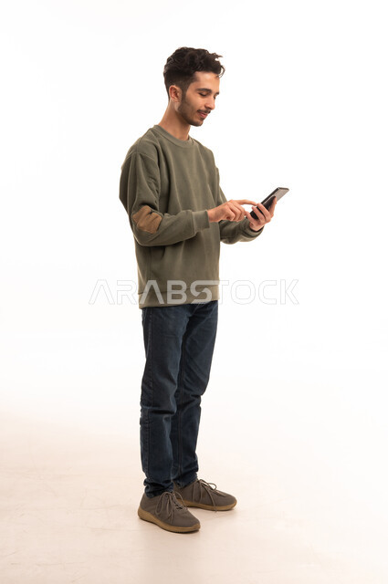 شاب سعودي يستخدم الهاتف الذكي بخلفية بيضاء