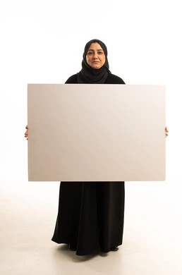 امرأة عربية تحمل لوحة بيضاء فارغة في استوديو التصوير