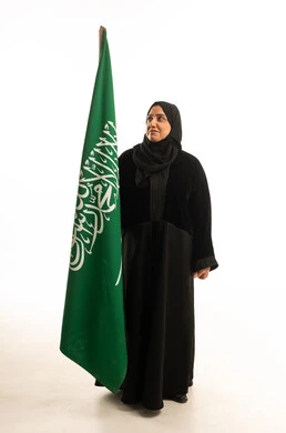 امرأة سعودية بالعباءة مع العلم الوطني