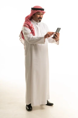 رجل سعودي بالزي التقليدي يستخدم الهاتف الذكي