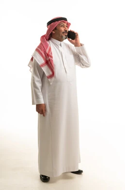رجل سعودي بالثوب التقليدي يتحدث في الهاتف المحمول بالاستوديو