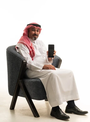 رجل سعودي بالزي التقليدي يحمل هاتف ذكي